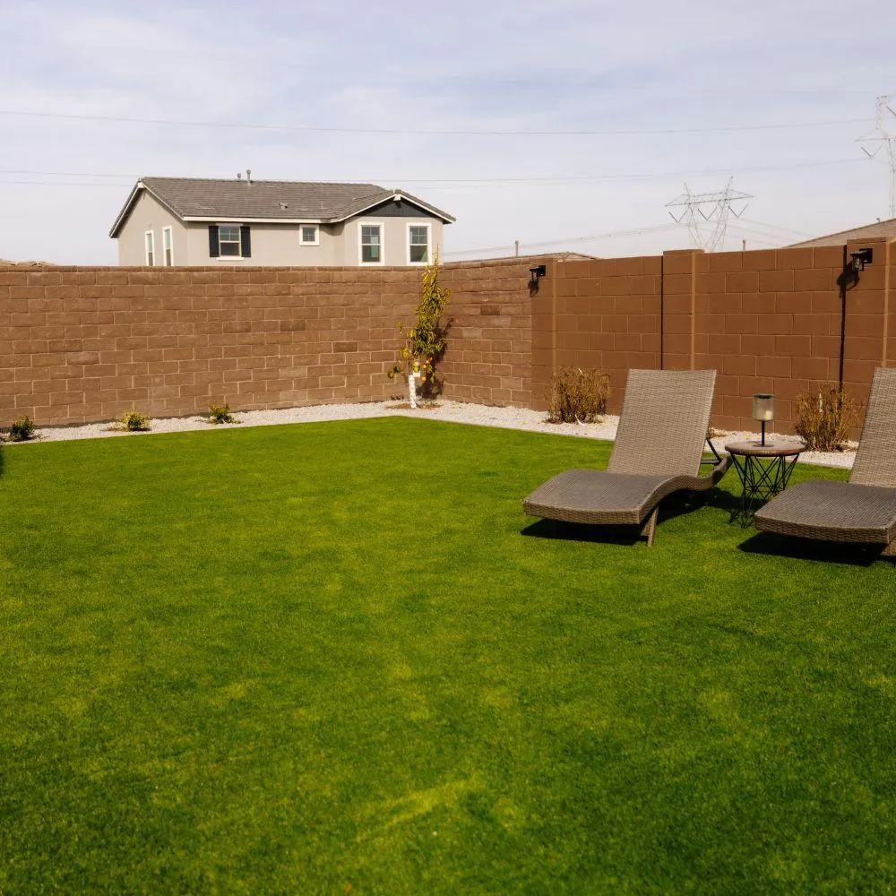 Turf backyard with block wall and lounge chairs