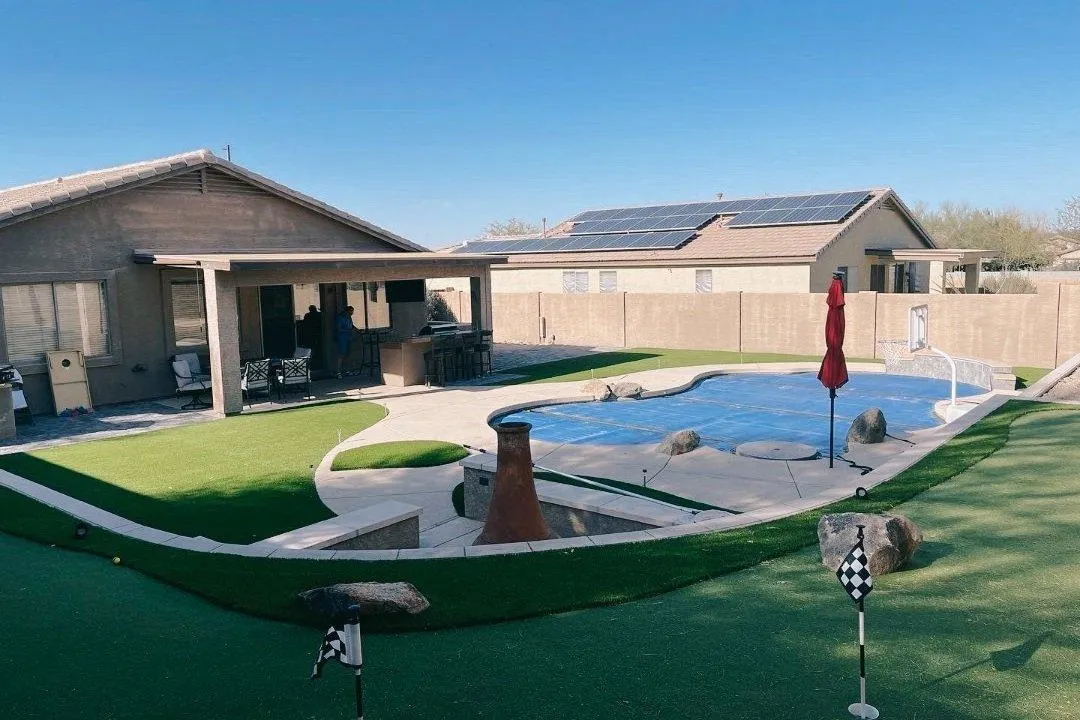 Backyard putting green with pool and outdoor kitchen