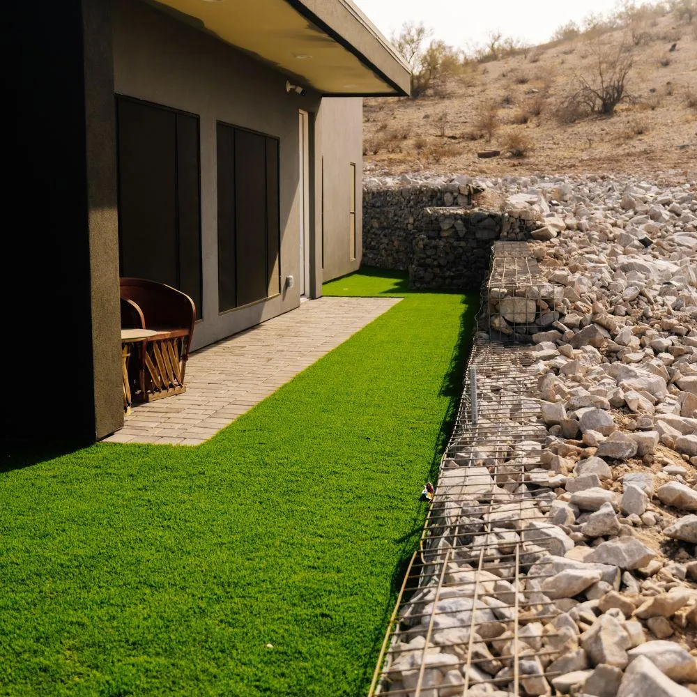 Turf side yard with gabion wall separating desert wash
