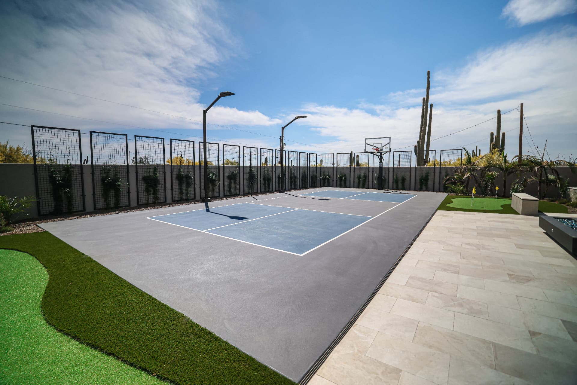 Backyard sport court with basketball hoop, turf putting green, and pavers