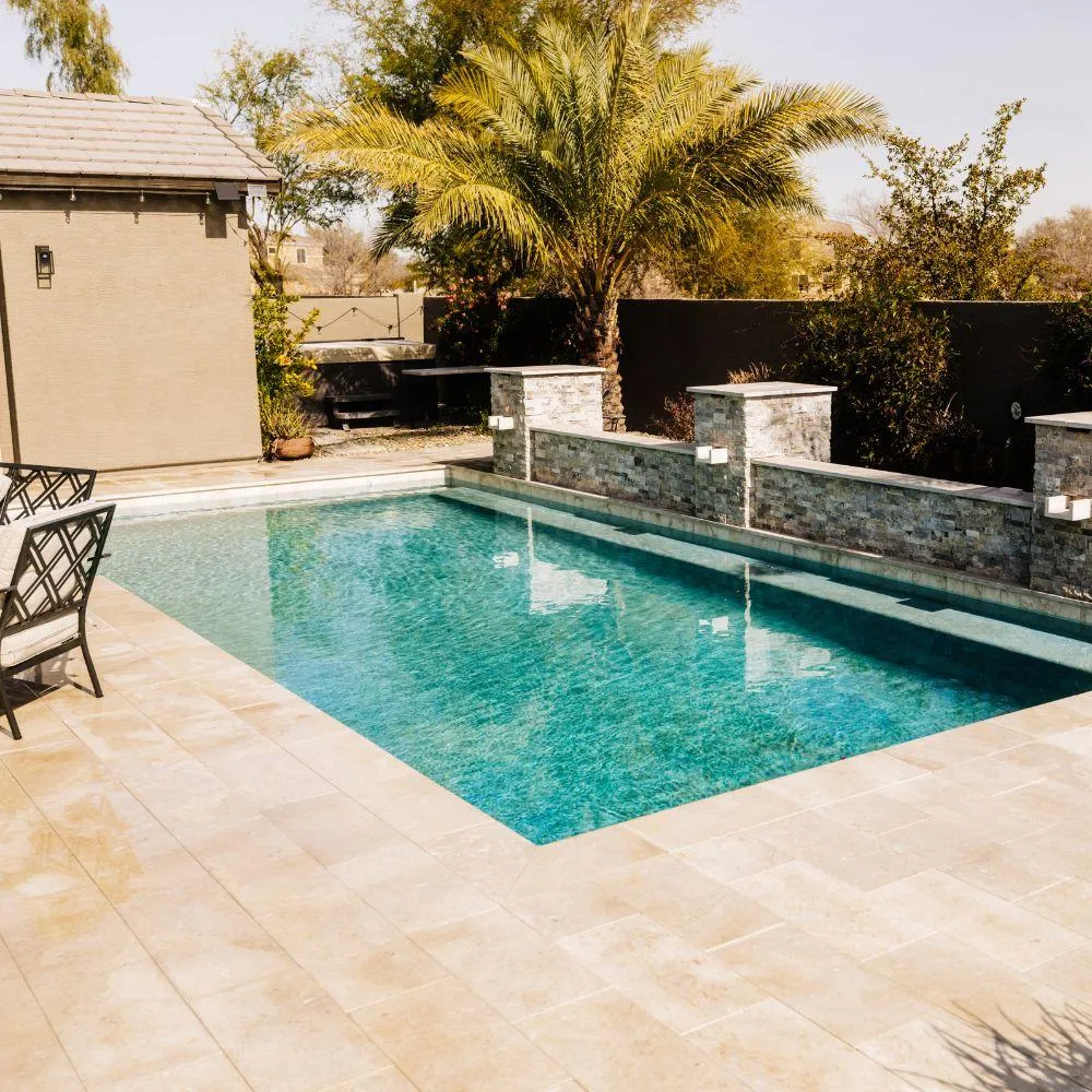 Rectangular pool with stacked stone accent walls and travertine deck