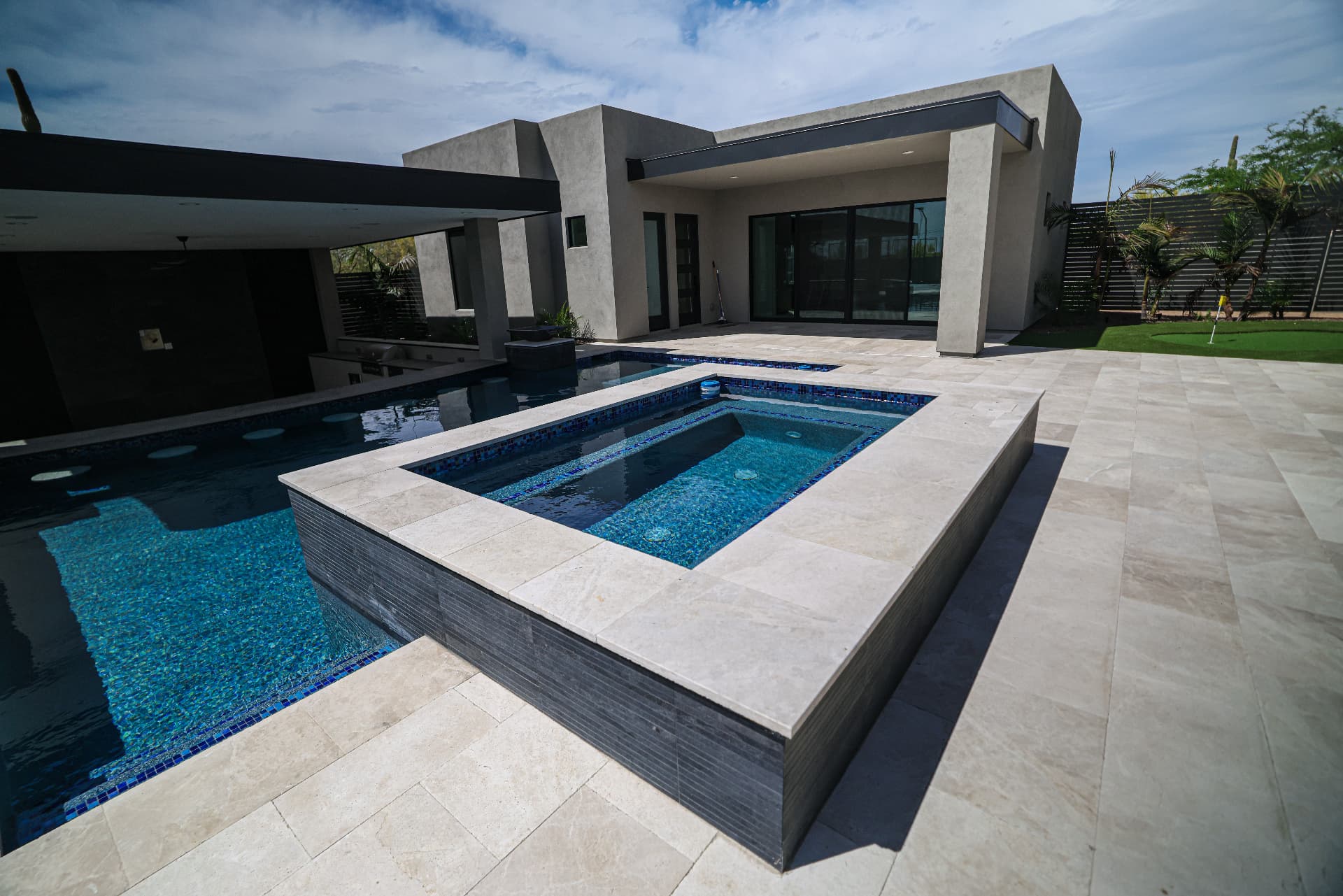 Modern home with custom pool, raised spa, and travertine paver deck