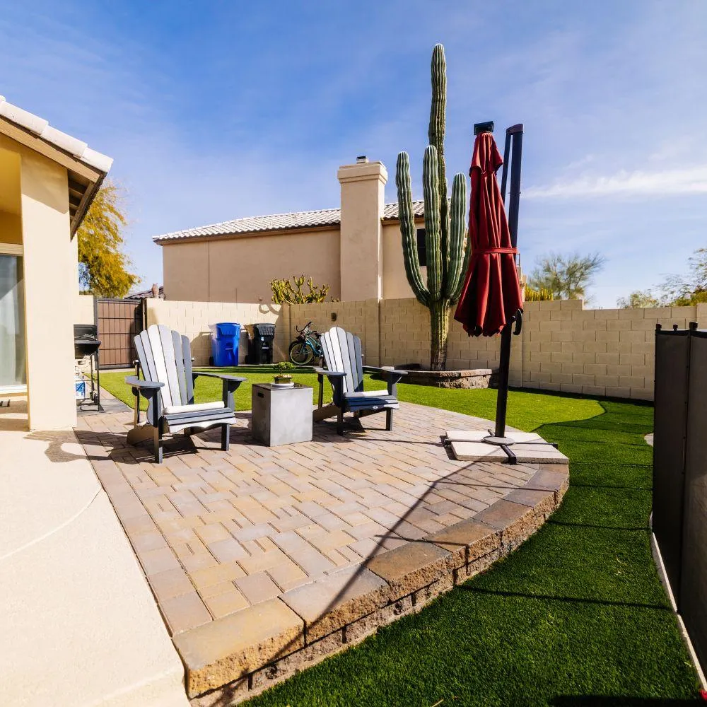 Paver patio with adirondack chairs, cactus, and turf lawn