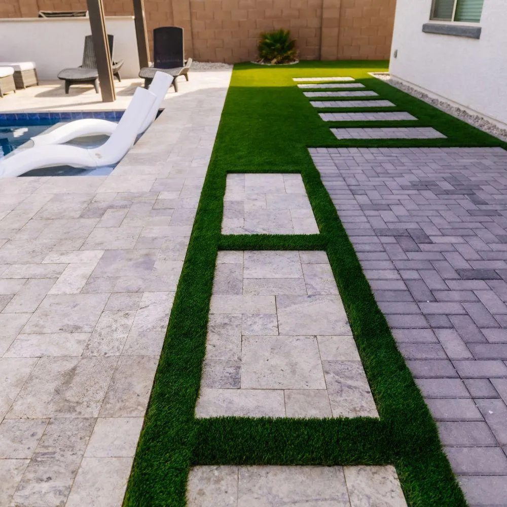 Travertine paver deck with turf inlay bands beside pool