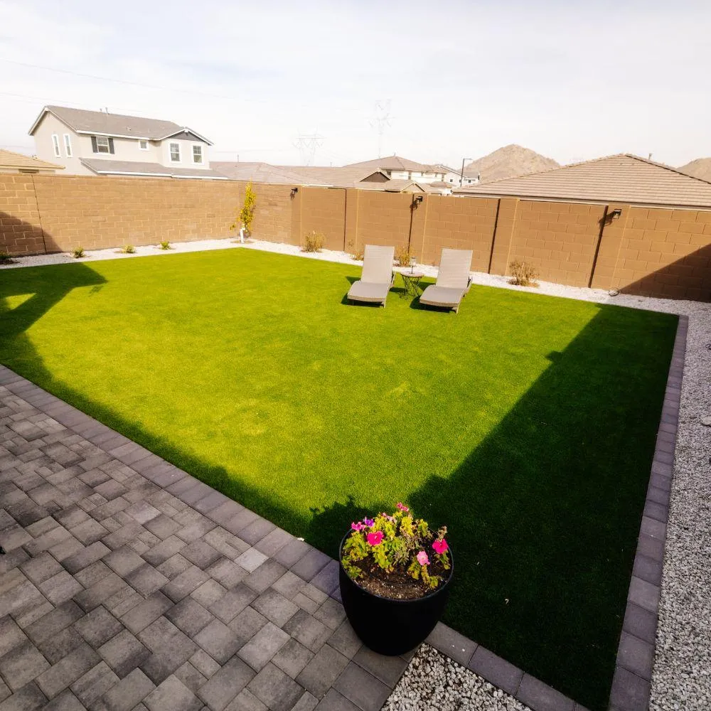 Turf backyard with pavers and lounge chairs