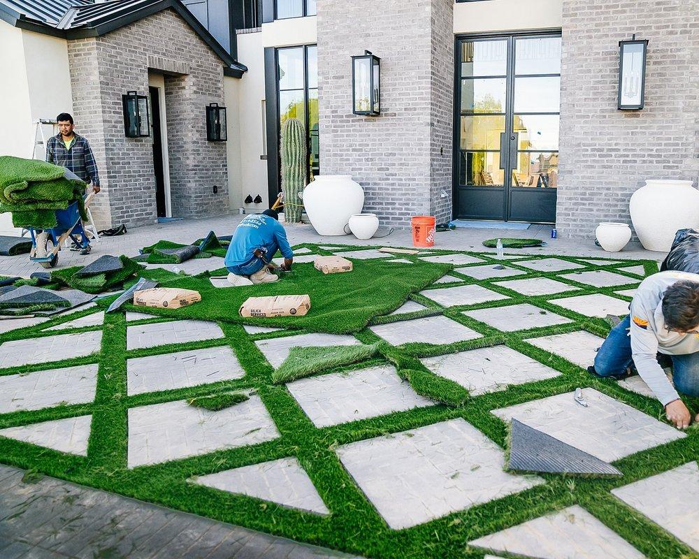 Crew installing turf inlay pattern between pavers