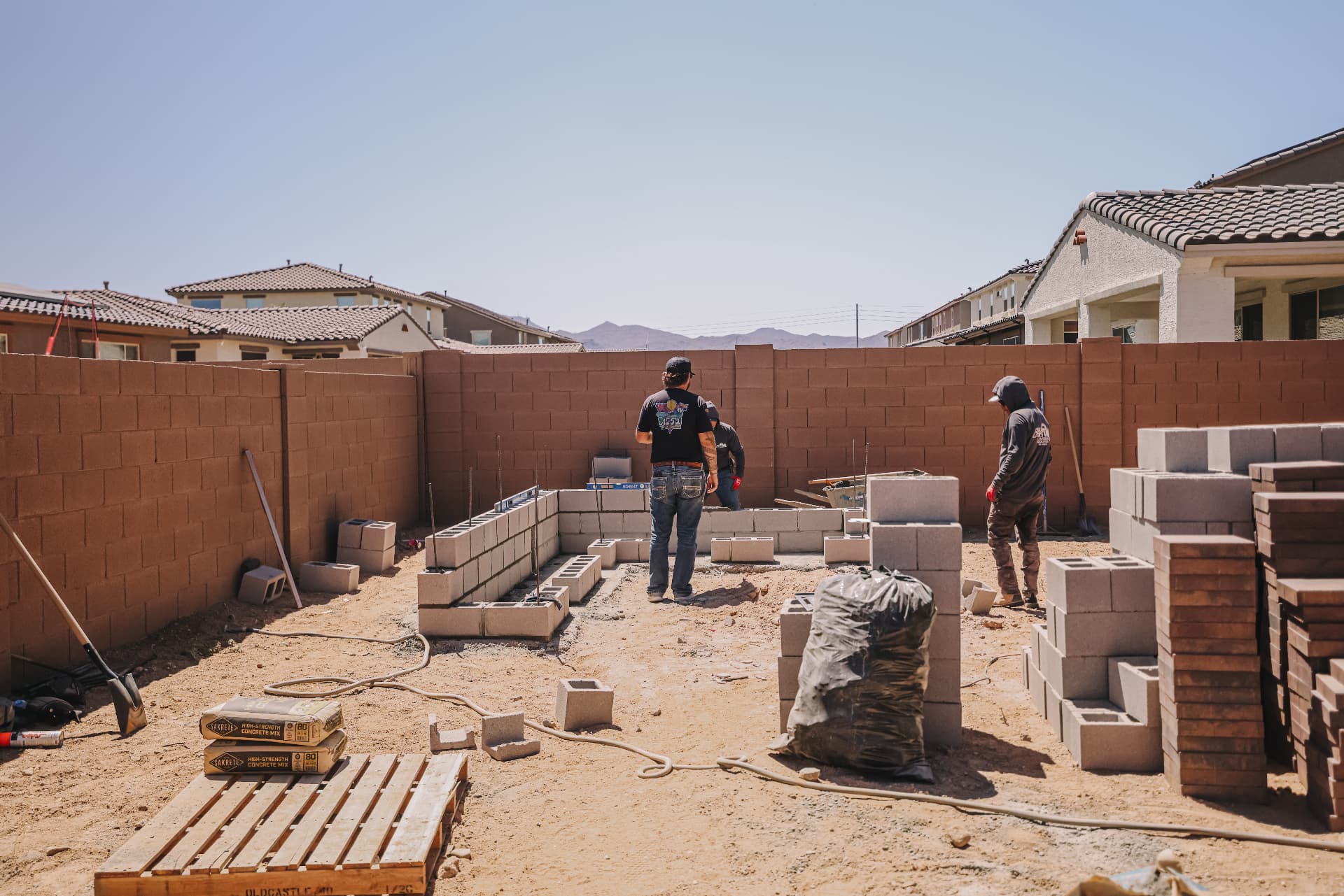 Crew laying block wall footings on an active backyard build