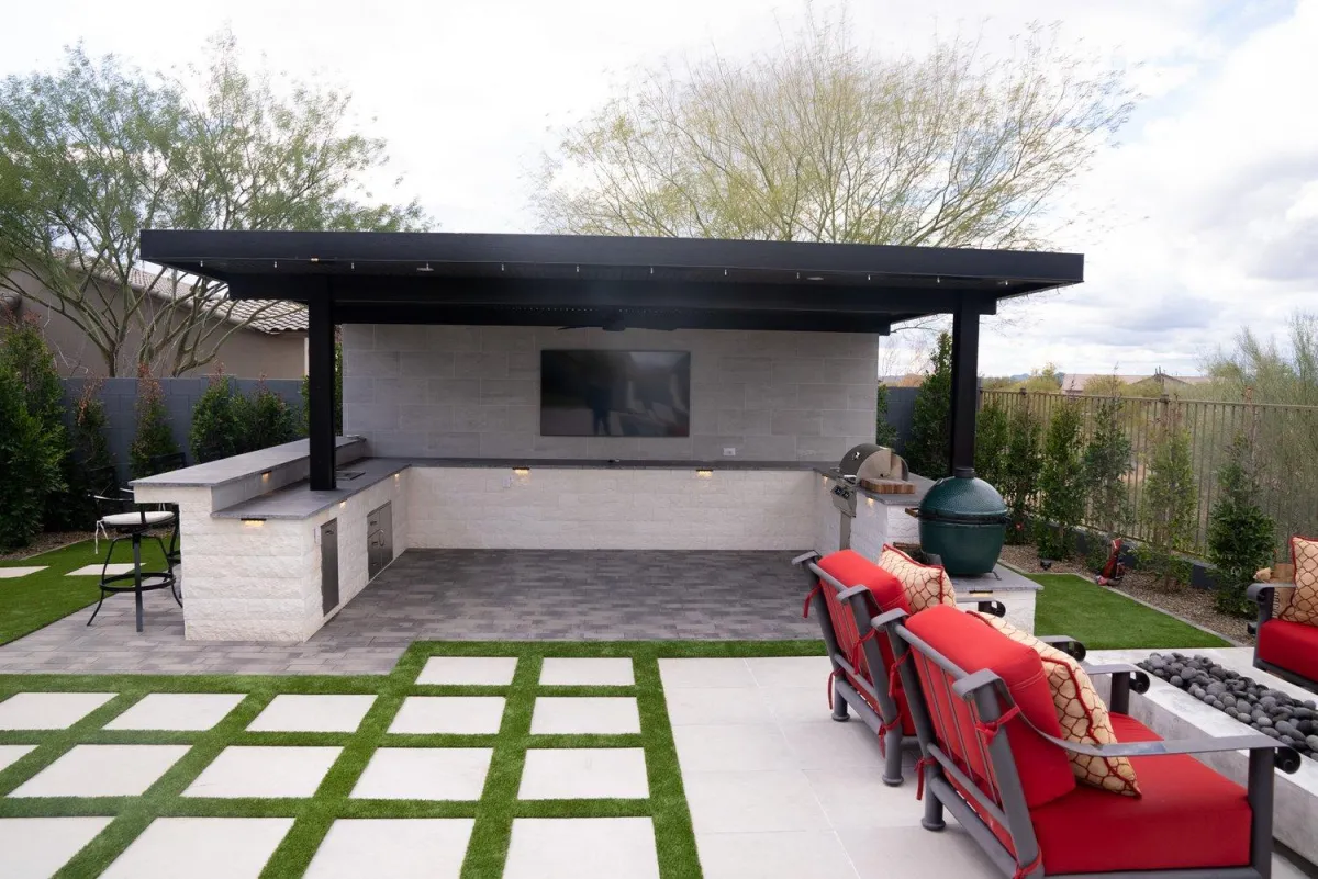 Covered outdoor living room with kitchen, TV, and paver patio