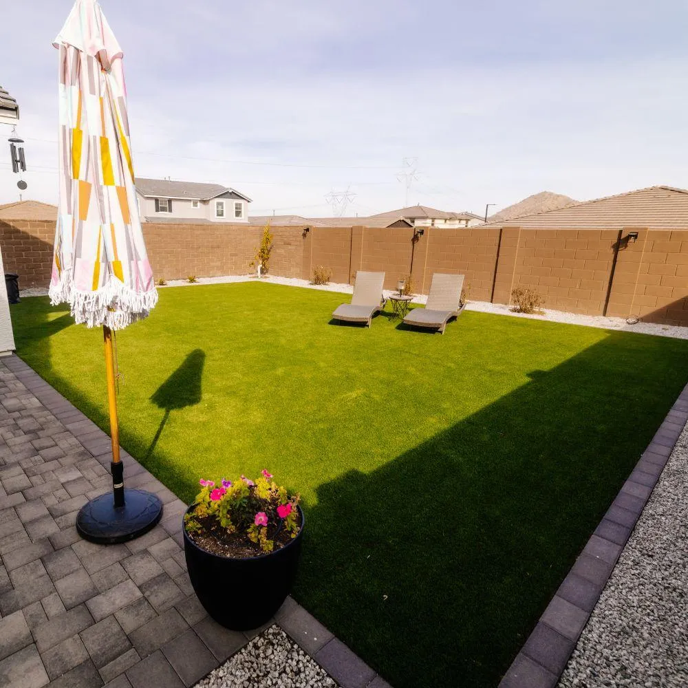 Backyard turf lawn with paver patio and lounge chairs