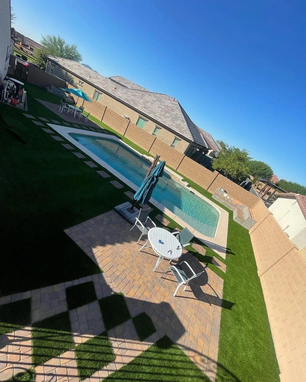 Aerial view of pool, pavers, and turf backyard